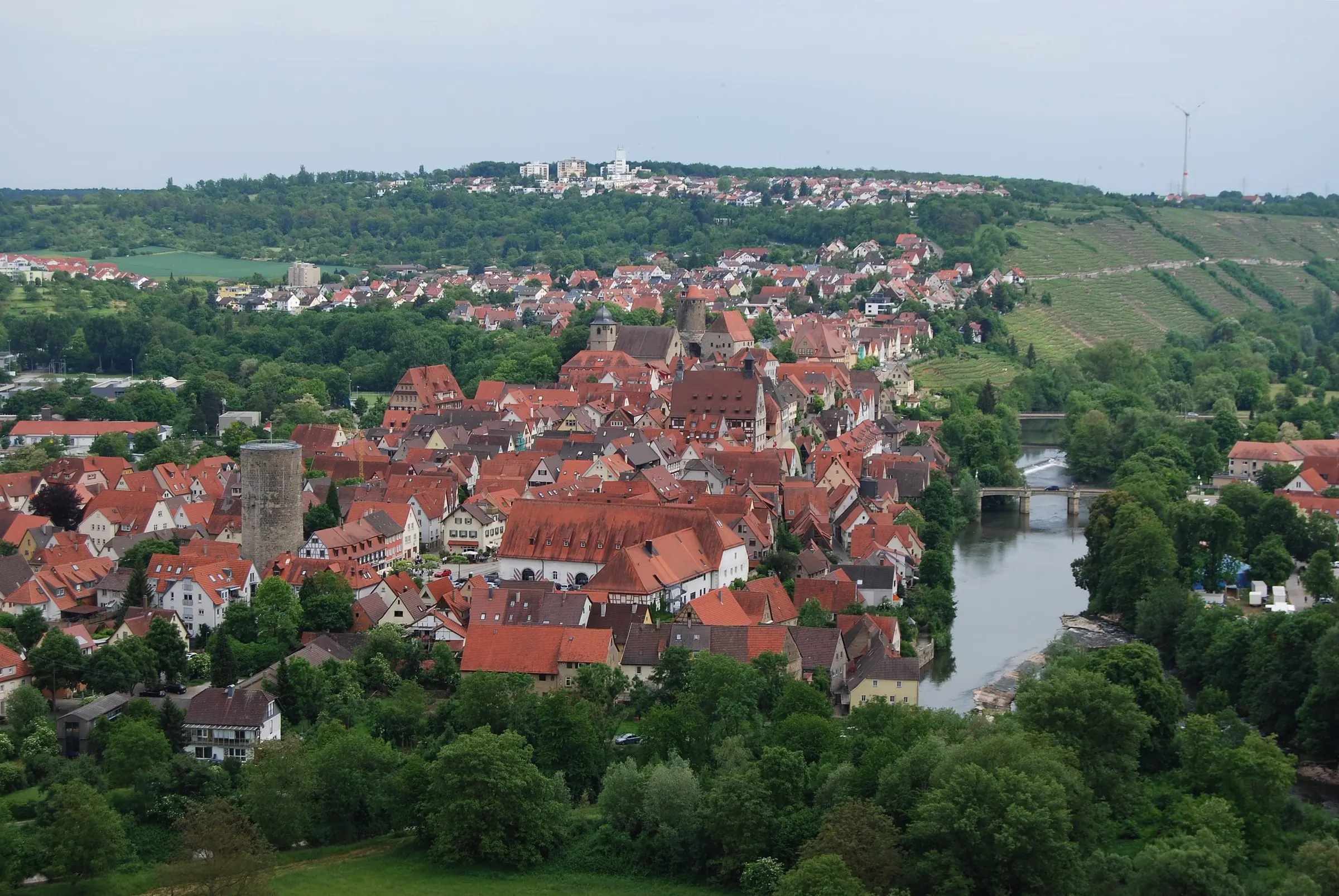 Blick über die Altstadt von Besigheim mit roten Ziegeldächern, einem runden Turm, dem Fluss und Weinbergen am Hang